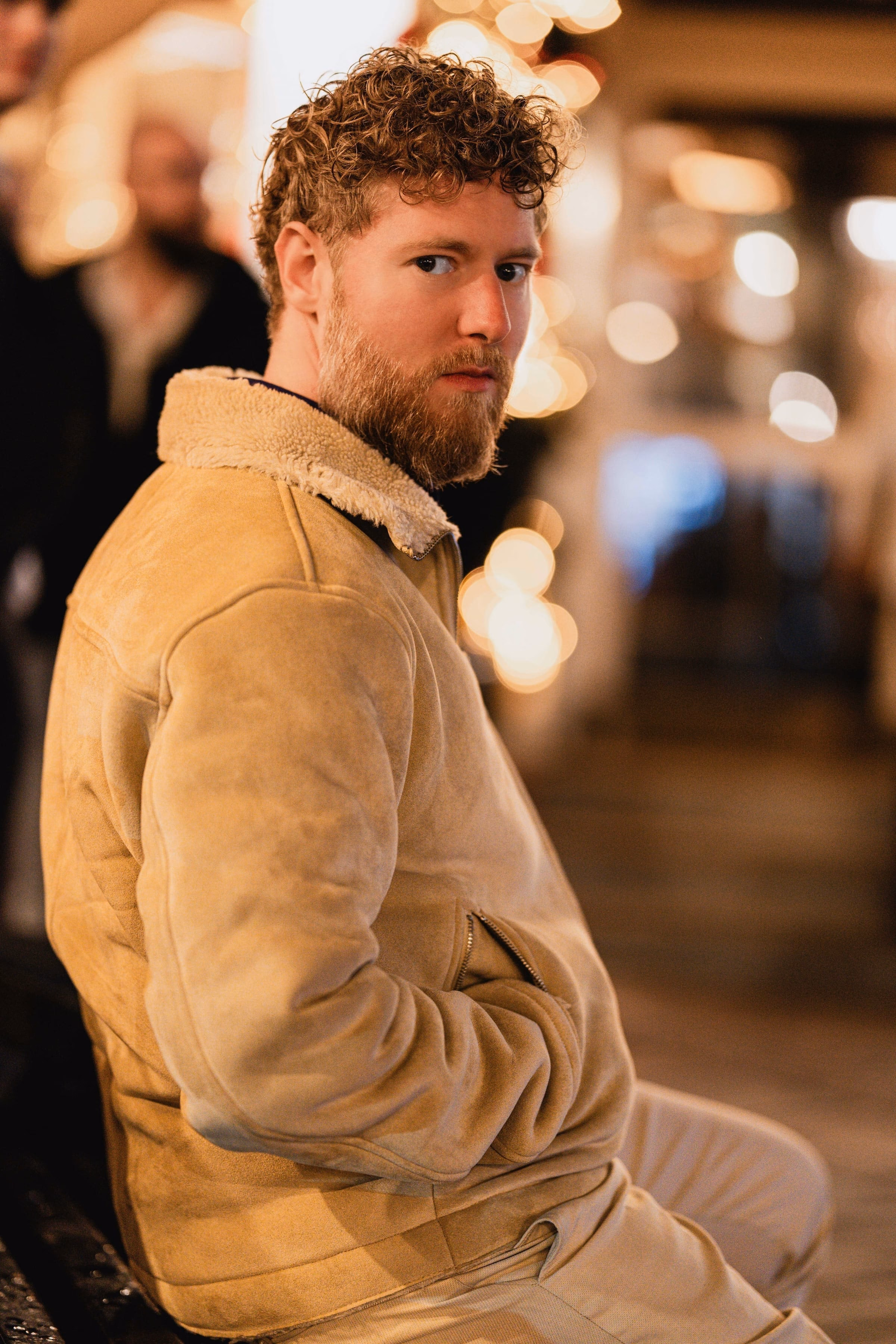 Benjamin Weidig in beiger Jacke, über die Schulter blickend